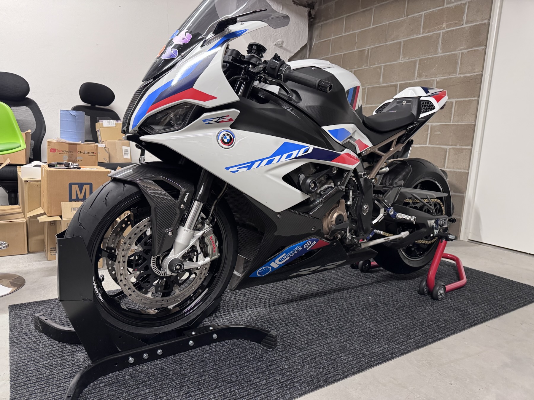 White S 1000 RR on front and rear paddock stands in a home garage