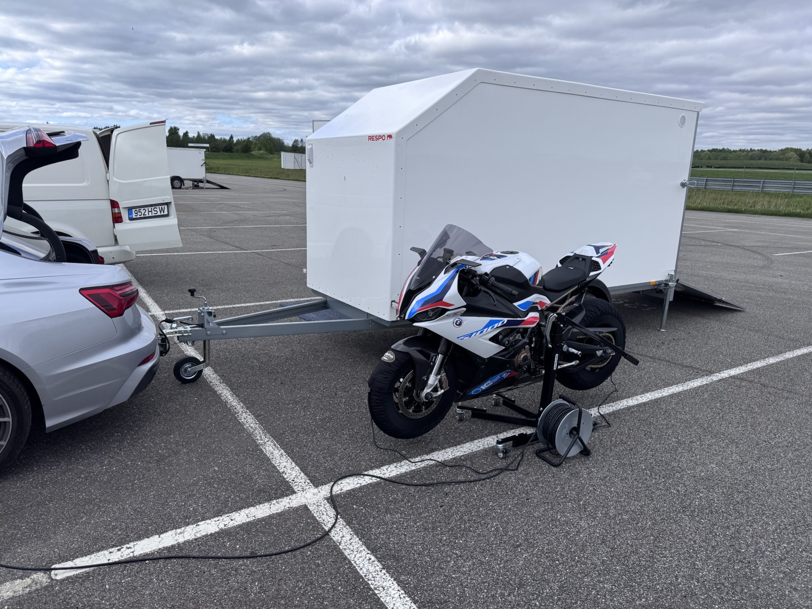 Bike on paddock stands next to the trailer with tyre warmers plugged in