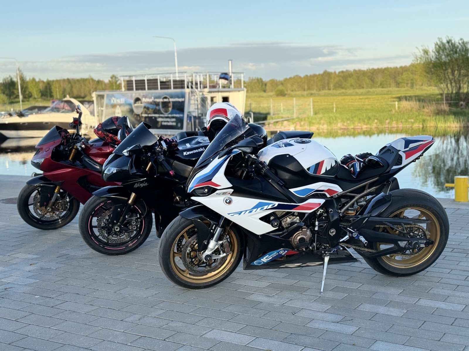 The S 1000 RR with gold wheels parked beside two other sport bikes by a lake