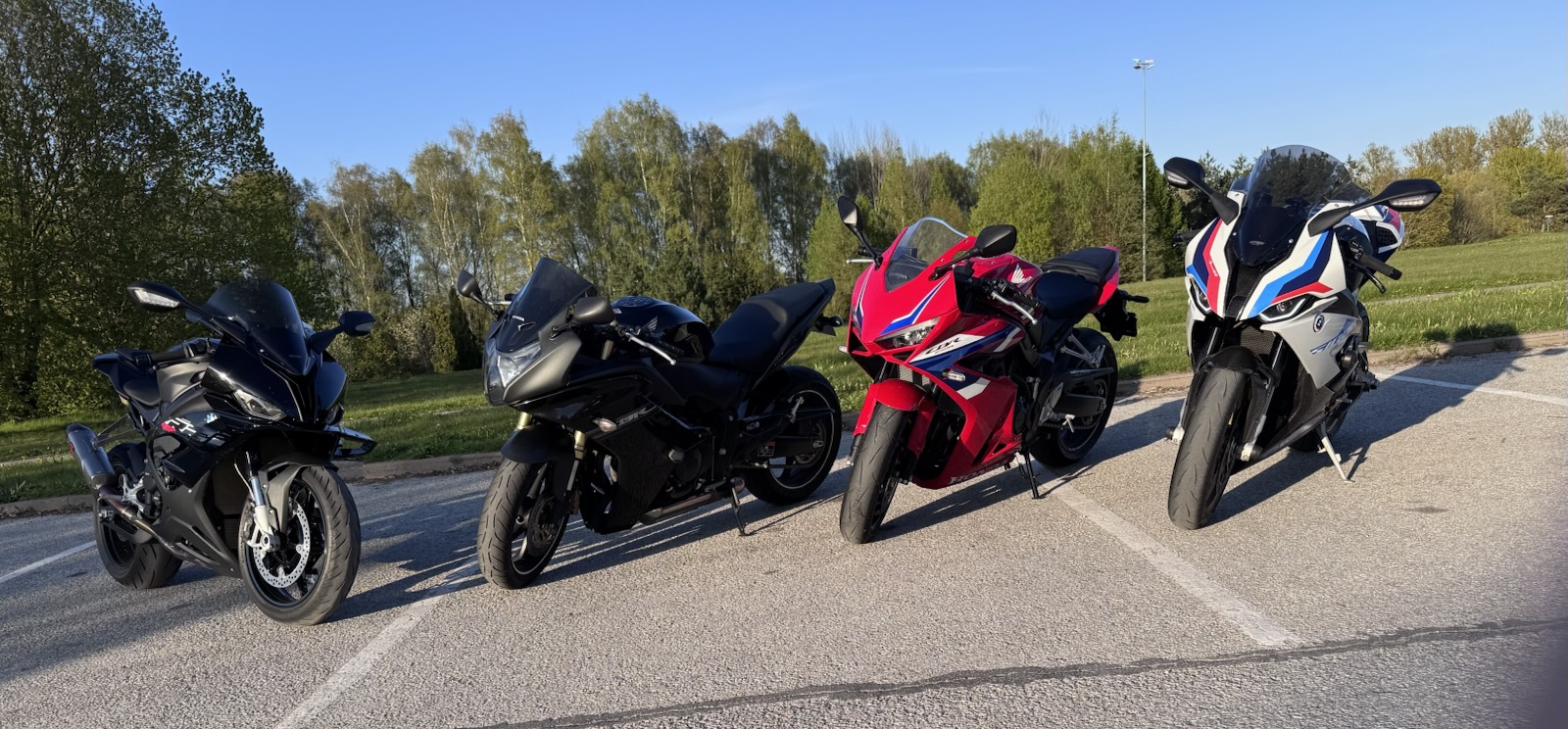 Four sport bikes lined up in a car park under a blue spring sky, the S 1000 RR on the right