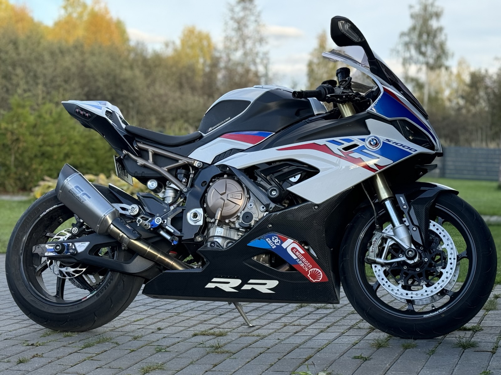 Side profile of the S 1000 RR on paving stones with autumn trees behind