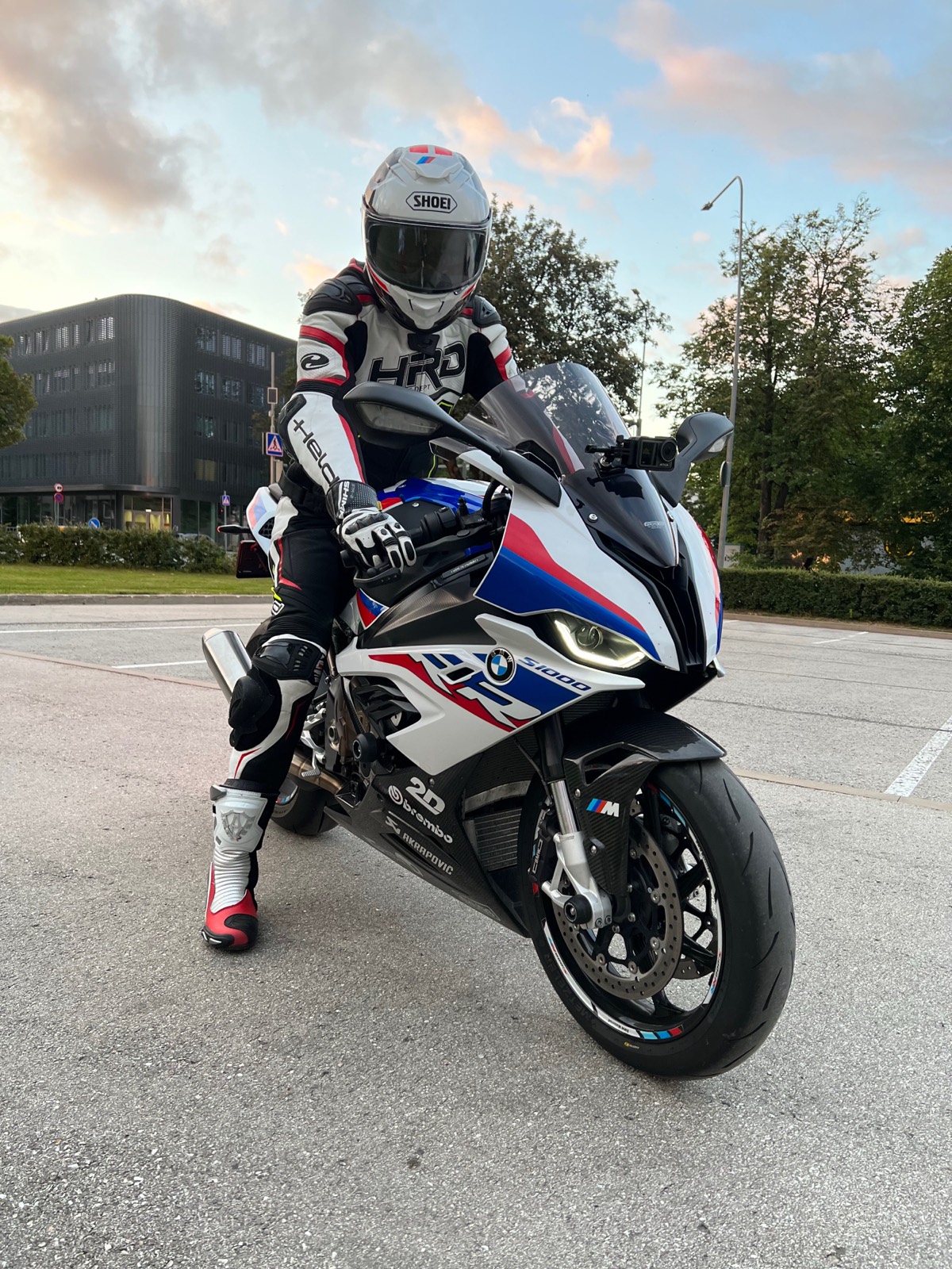 Rider in full leathers and helmet sitting on the S 1000 RR in an empty car park at sunset