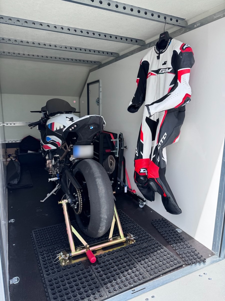 Bike strapped in the trailer with one-piece leathers hanging beside it