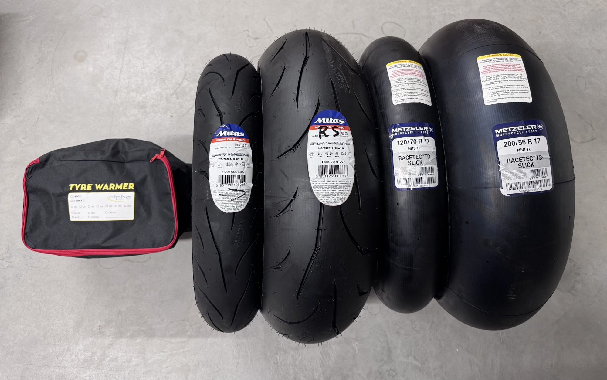 Tyre warmer bag next to a Mitas road tyre pair and Metzeler Racetec TD slicks, 120/70 R17 front and 200/55 R17 rear