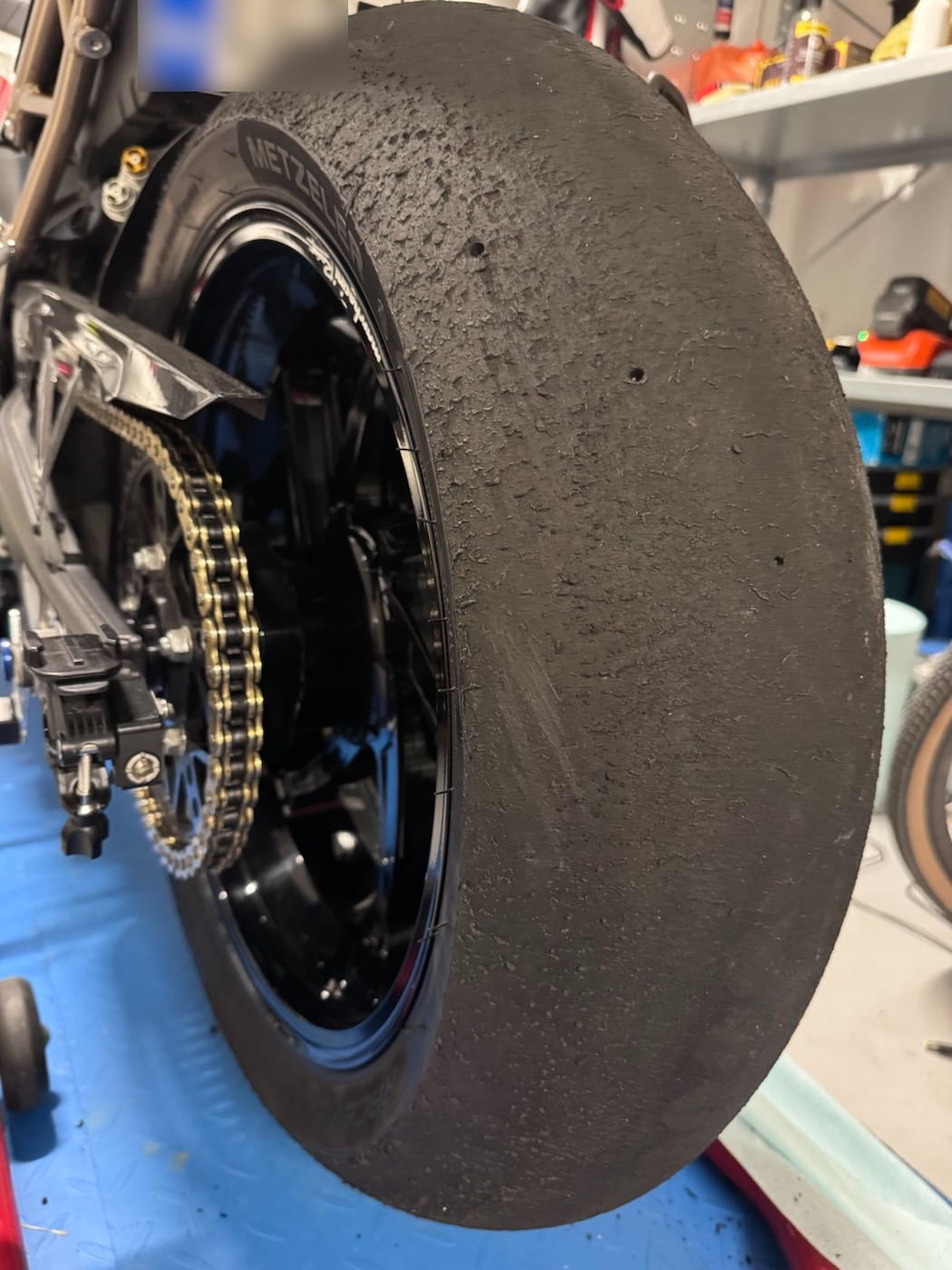 Close-up of a used rear slick with torn rubber, in the workshop