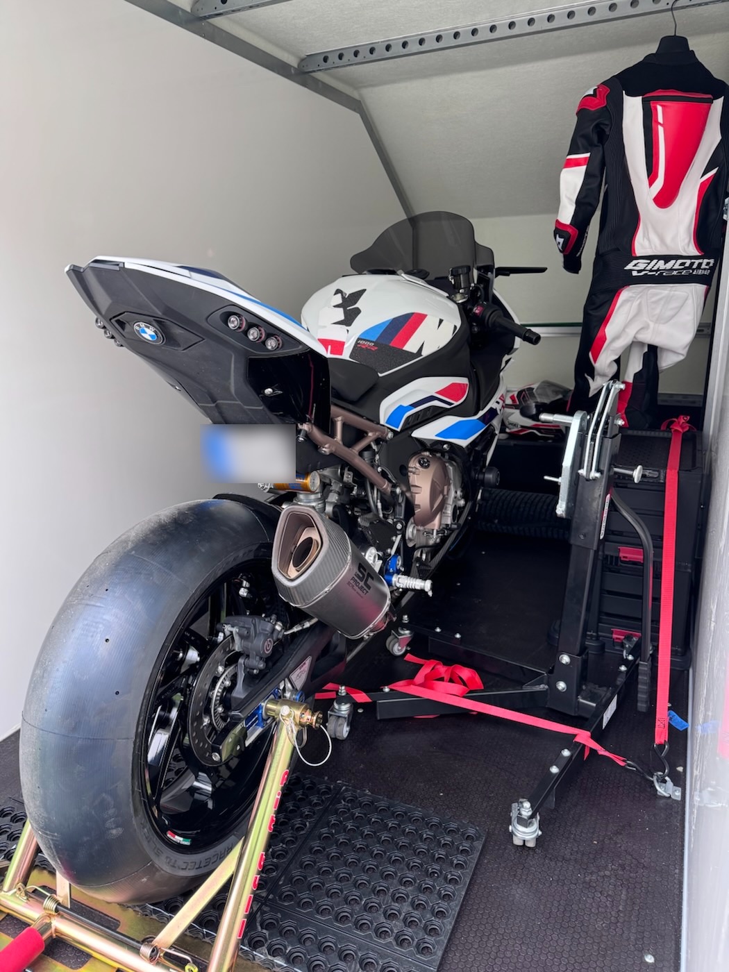 Bike in the trailer with one-piece leathers hanging alongside