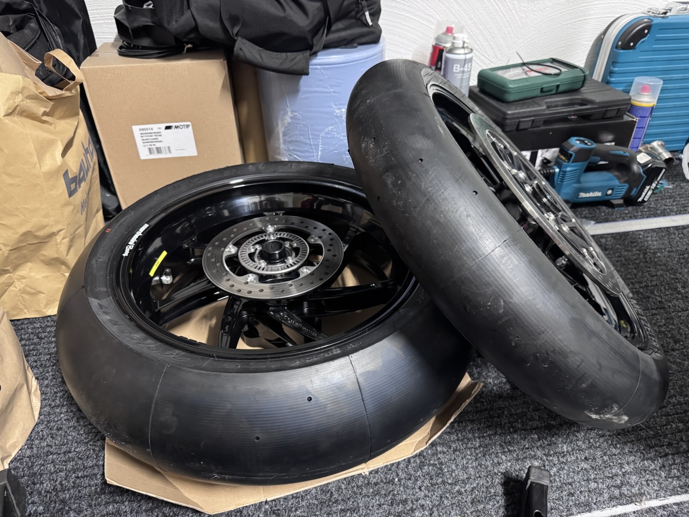 Two black wheels fitted with slicks lying on the workshop floor